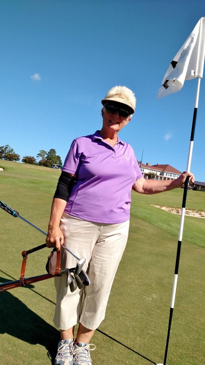 Darlind Davis, holding The Handle, stands at the 2nd green of The Cradle.